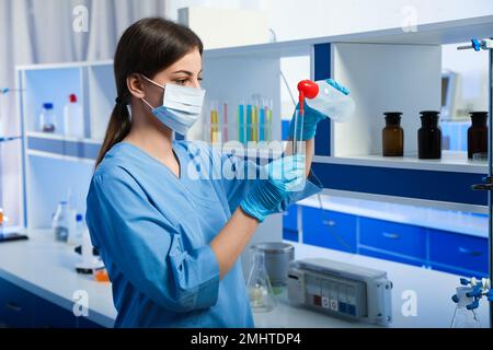 Wissenschaftler gießen Flüssigkeit in das Reagenzglas in Innenräumen. Laboranalysen Stockfoto