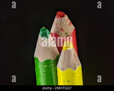 Großaufnahme-Buntstifte rot, gelb und grün auf schwarzem Hintergrund. Stockfoto