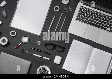 Flache Verlegung mit Laptop und Schreibwaren auf schwarzem Hintergrund. Arbeitsplatz des Designers Stockfoto