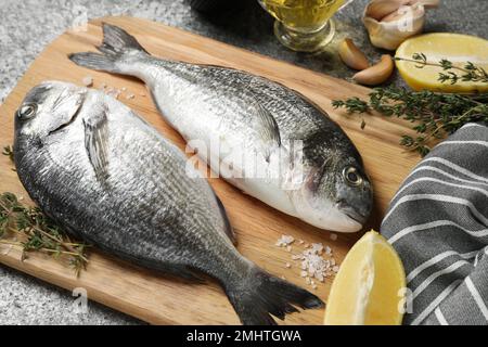 Roher dorada-Fisch und Zutaten auf grauem Tisch Stockfoto