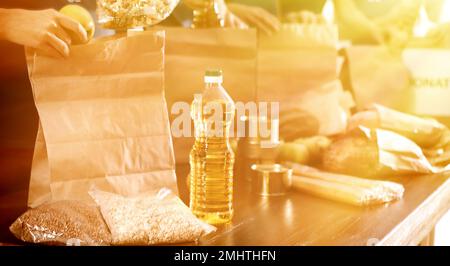 Team von Freiwilligen, die Essensspenden am Tisch im sonnenbeleuchteten Raum sammeln, Nahaufnahme Stockfoto