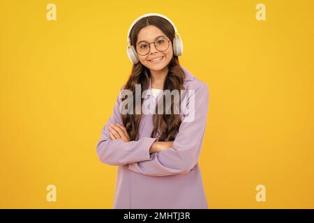 Kindermusik-Konzept. Teenager Kind Mädchen tanzt im Rhythmus der Melodie, hört Lied in Kopfhörern. Kind hört Musik über Kopfhörer. Stockfoto