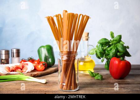 Glas mit ungekochten Buchweizennudeln und frischen Zutaten auf einem Holztisch Stockfoto