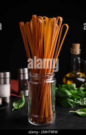 Ungekochte Buchweizen-Nudeln und frische Zutaten auf schwarzem Tisch Stockfoto