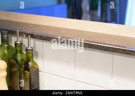 Marmorsteinregal in der Inselküche. Weiße Fliesen, Flaschen Pflanzenöl. Stockfoto
