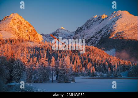 Der frische, klare Wintermorgen im Strbske Pleso, mit der hohen Tatra über dem gefrorenen See Stockfoto