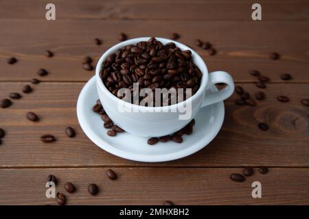 Geröstete Kaffeebohnen in einer Kaffeetasse auf dem Tisch Stockfoto