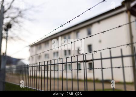 Freiburg, Deutschland. 27. Januar 2023. Ein teilweise mit Stacheldraht versehener Zaun umgibt das Gelände der ursprünglichen staatlichen Aufnahmeeinrichtung (LEA) in Freiburg. Nach Unruhen in der Freiburger Flüchtlingsanlage werden Lösungen gesucht. Die Staatsanwaltschaft, die Polizei und der regionalrat sind beteiligt, und zu diesem Zweck wurde auch eine Sitzung geplant. Seit dem Wochenende gab es mehrere Unruhen in der ursprünglichen Auffangeinrichtung. Kredit: Philipp von Ditfurth/dpa/Alamy Live News Stockfoto