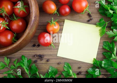 Kirschtomaten auf Holzhintergrund mit Petersilie, Gewürzen und einem Notizbuch zum Schreiben eines Rezepts. Rezepte Konzept mit Tomaten, Konserven. Speicherplatz kopieren Stockfoto