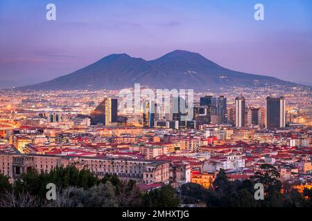 Neapel, Italien mit der Skyline des Finanzviertels unter dem Berg Vesuv in der Dämmerung. Stockfoto