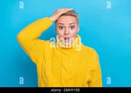 Foto einer verblüfften peinlichen Dame mit warmer Komfortkleidung, beeindruckt von schlechten Nachrichten, isoliert auf blauem Hintergrund Stockfoto