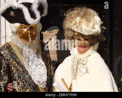 Venedig Karneval, Maskenparade auf der Piazza San Marco, reifes Paar mit Kostüm aus dem 18. Jahrhundert, gekleidet in Gold, Schwarz und Weiß, glücklich und Smili Stockfoto