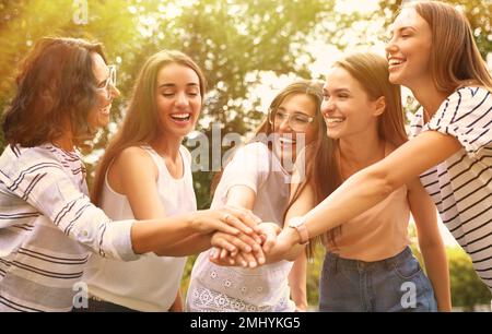 Fröhliche Freiwillige, die sich an sonnigen Tagen im Freien die Hände zusammentun Stockfoto