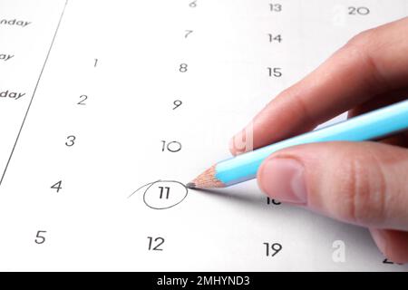 Frau markiert Datum im Kalender mit Bleistift, Nahaufnahme Stockfoto
