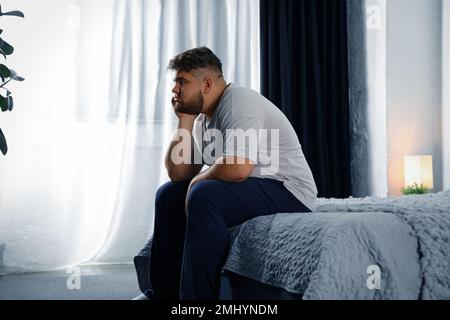 Deprimierter übergewichtiger Mann im Bett zu Hause Stockfoto