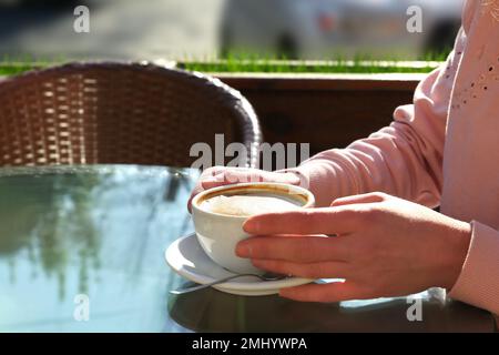 Frau mit einer Tasse frischen aromatischen Kaffees am Tisch im Café Stockfoto