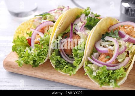 Leckere Fisch-Tacos, serviert auf einem weißen Holztisch, Nahaufnahme Stockfoto