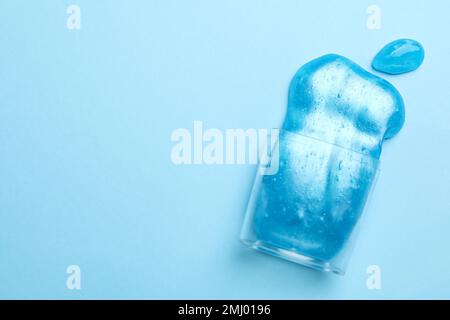 Umgedrehter Kunststoffbehälter mit hellem Schleim auf hellblauem Hintergrund, Draufsicht. Platz für Text Stockfoto