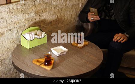 Mann trinkt türkischen Tee im Café und Telefon in der Hand Stockfoto