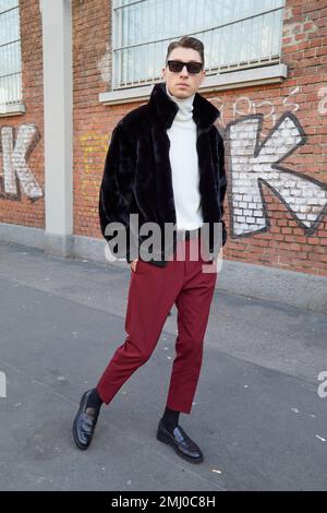 MAILAND, ITALIEN - 14. JANUAR 2023: Mann mit schwarzer Pelzjacke und weißem Rollkragenpullover vor der Fendi-Modenschau, Mailand Fashion Week Street Style Stockfoto