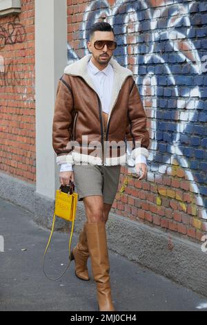 MAILAND, ITALIEN - 14. JANUAR 2023: Mann mit brauner und weißer Schafsleder-Jacke und Shorts vor der Fendi-Modenschau, Mailand Fashion Week Street Style Stockfoto
