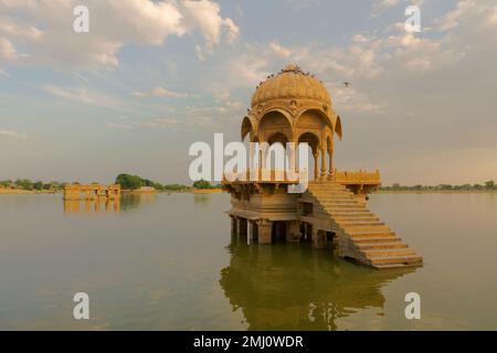 Chhatris und Schreine der hinduistischen Götter und Göttinnen am Gadisar-See, Jaisalmer, Rajasthan, Indien mit Reflexion über Wasser. Indoislamische Architektur. Stockfoto