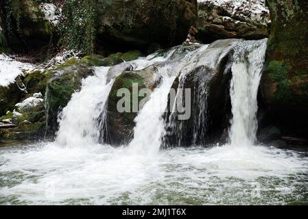 Scheissendempel-Wasserfall, Fluss Black Ernz mit schneebedeckter Steinbrücke, Müllerthal-Pfad in Waldbillig, Luxemburg im Winter Stockfoto