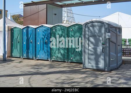 Sechs Kunststoff-Toiletten in verschiedenen Farben. Öffentliche Toiletten auf dem Marktplatz. Stockfoto