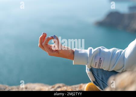 Hand- und Seegeschgen. Konzept gesunder Lebensstil Konzept - Hand meditierender Yoga-Frau zeigt Gyan Mudra über dem Meeresuntergang-Hintergrund Stockfoto