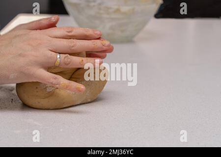 Nahaufnahme von Frauenhänden, die frischen Teig kneten, um Kekse in ihrer Küche zu backen Stockfoto