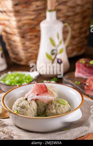 Canederli oder Knodel in Brühe mit grünen Zwiebeln. Traditionelles norditalienisches Gericht, typische Pasta für Trient, Alpen, Südtirol, italienische und österreichische Küche. Vertikal Stockfoto