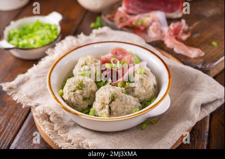 Canederli oder Knodel in Brühe mit grünen Zwiebeln. Traditionelles norditalienisches Gericht, typische Pasta für Trient, Alpen, Südtirol, italienische und österreichische Küche. Stockfoto