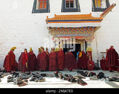 Mönche mit gelben Kappen und Schuhe in der Gebetshalle, Labrang Tibetanerkloster, Xiahe, Provinz Gansu, China Stockfoto