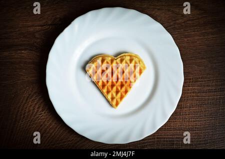 Herzförmige Waffel auf dem Teller. Frühstück am Valentinstag. Liebeskonzept. Stockfoto