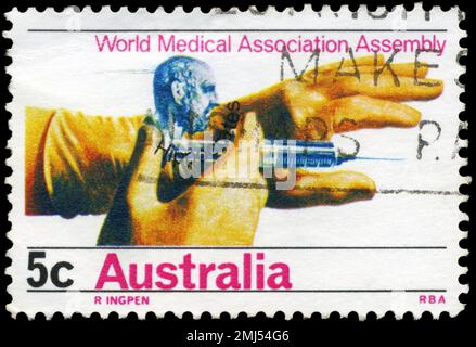 AUSTRALIEN - CIRCA 1968: Ein in AUSTRALIEN gedruckter Stempel zeigt die Hippokrates und Hände halten Hypodermic, Generalversammlung der Weltärztekammer Stockfoto