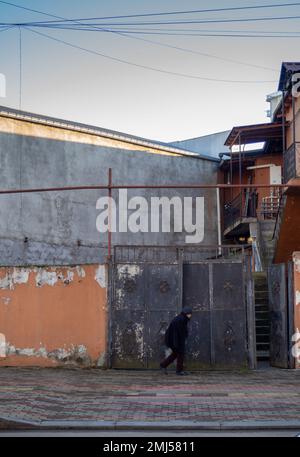 Batumi, Georgia. 01.10.2023 Bettlerin geht gegen die Wand. Einheimischer in der Altstadt. Der Haushalt. Der Innenhof ist alt in Batumi. Stockfoto