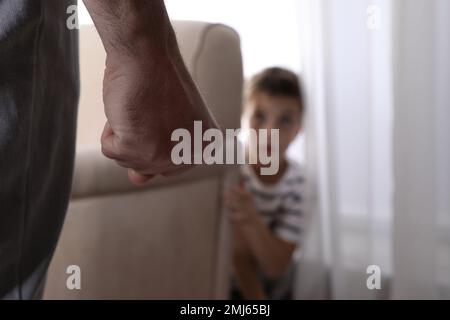 Der Mann bedroht seinen Sohn zu Hause, konzentrier dich auf die Faust. Das Konzept der häuslichen Gewalt Stockfoto