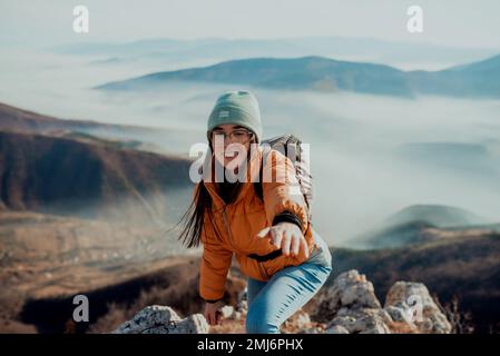 Menschen helfen sich gegenseitig, bei Sonnenaufgang einen Berg hinauf zu wandern. Stockfoto