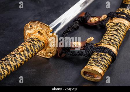 Japanisches Samurai Katana-Schwert und Scheide aus nächster Nähe. Foto einer Waffe in Low-Key mit selektivem Fokus Stockfoto