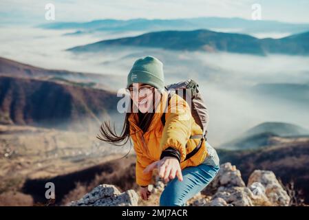 Menschen helfen sich gegenseitig, bei Sonnenaufgang einen Berg hinauf zu wandern. Stockfoto