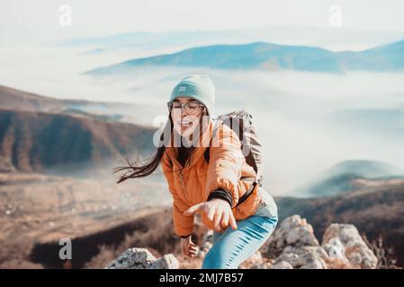 Menschen helfen sich gegenseitig, bei Sonnenaufgang einen Berg hinauf zu wandern. Stockfoto