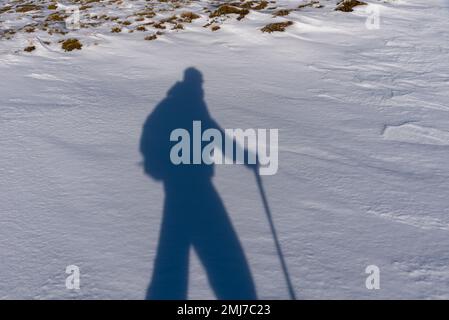 Schatten eines Bergsteigers im Schneewandern mit Rucksack und Stock auf der Südseite der Sierra Nevada.Granada. Stockfoto