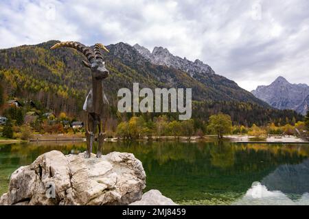 Statue eines Steinbocks am Jasna-See in Kranjska Gora mit einer atemberaubenden Herbstlandschaft und Bergregionen im Hintergrund. Slowenien. Stockfoto