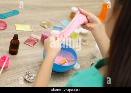 Kleines Mädchen, das Heimwerker-Schleim-Spielzeug am Tisch macht, Nahaufnahme Stockfoto