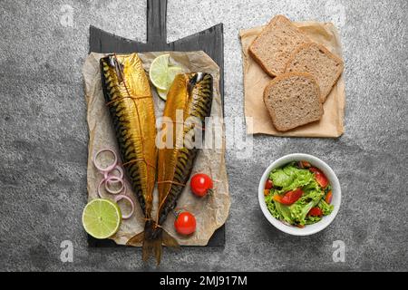 Flache Liegezusammensetzung mit leckerem Räucherfisch auf grauem Tisch Stockfoto