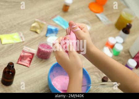 Kleines Mädchen, das Heimwerker-Schleim-Spielzeug am Tisch macht, Nahaufnahme Stockfoto