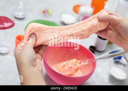 Kleines Mädchen, das Heimwerker-Schleim-Spielzeug am Tisch macht, Nahaufnahme Stockfoto