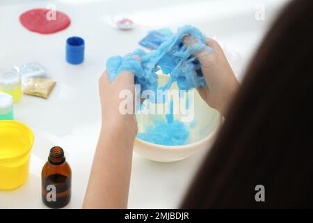 Kleines Mädchen, das Heimwerker-Schleim-Spielzeug am Tisch macht, Nahaufnahme Stockfoto