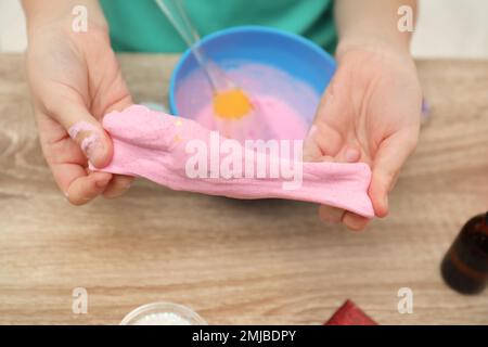 Kleines Mädchen, das Heimwerker-Schleim-Spielzeug am Tisch macht, Nahaufnahme Stockfoto