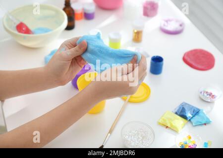 Kleines Mädchen, das Heimwerker-Schleim-Spielzeug am Tisch macht, Nahaufnahme Stockfoto